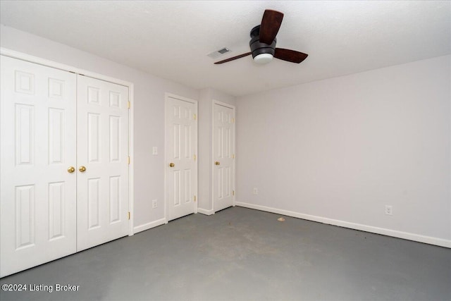 unfurnished bedroom featuring ceiling fan, a textured ceiling, and two closets