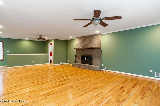 unfurnished living room with ceiling fan, light wood-type flooring, ornamental molding, and a brick fireplace