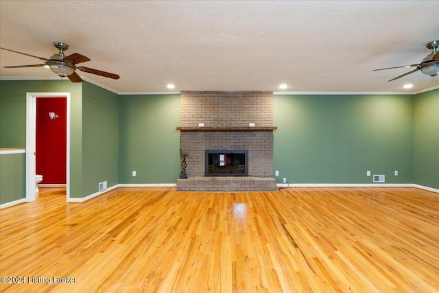 unfurnished living room featuring a fireplace, light hardwood / wood-style flooring, a textured ceiling, and ornamental molding