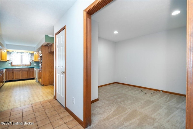 hallway featuring sink and light colored carpet