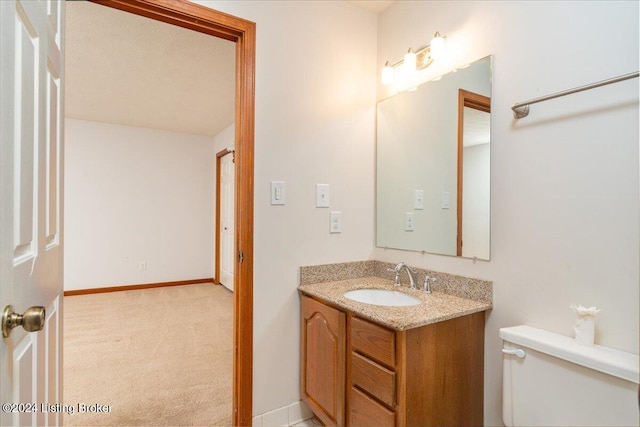 bathroom with a textured ceiling, vanity, and toilet