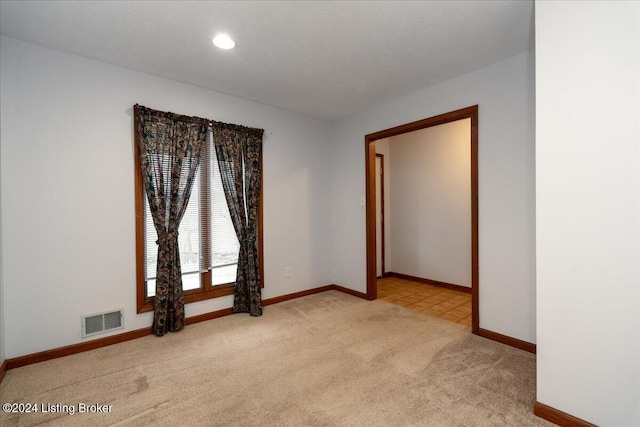 empty room featuring light colored carpet and a textured ceiling