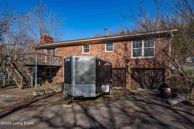 rear view of house with a wooden deck and a garage