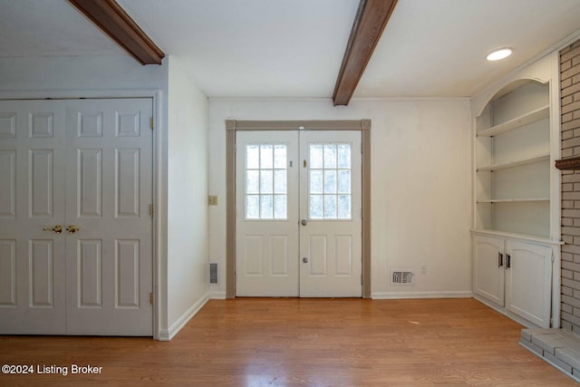 entrance foyer with french doors, beamed ceiling, and light wood-type flooring