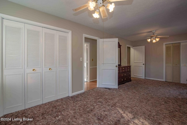 unfurnished bedroom with multiple closets, ceiling fan, carpet floors, and a textured ceiling