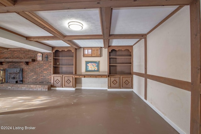 unfurnished living room with coffered ceiling, built in features, beamed ceiling, concrete floors, and a wood stove