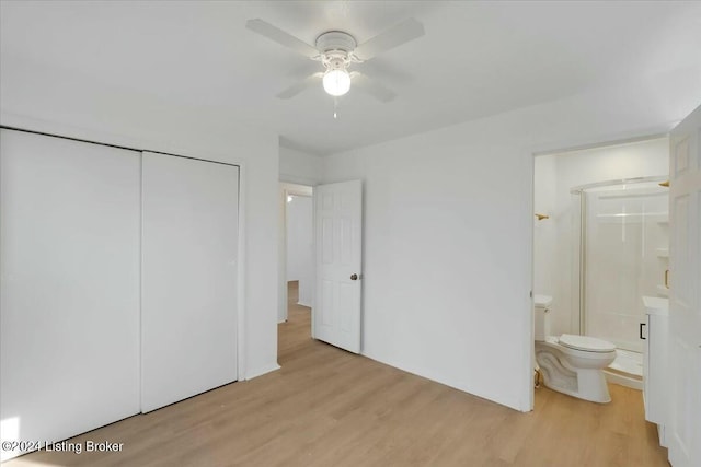 unfurnished bedroom featuring a closet, light hardwood / wood-style flooring, ensuite bath, and ceiling fan