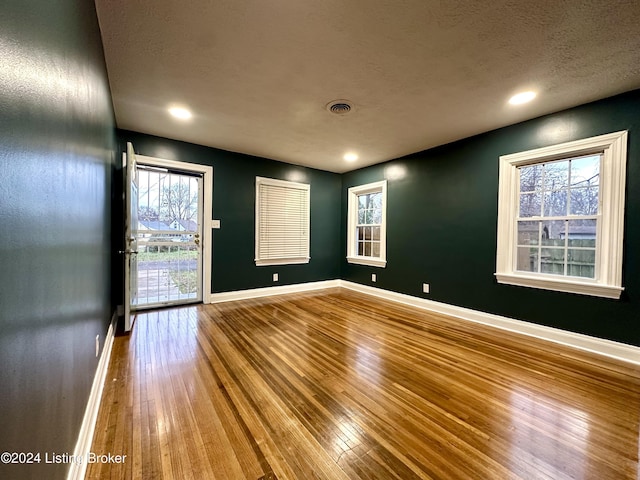 empty room with a textured ceiling and hardwood / wood-style flooring