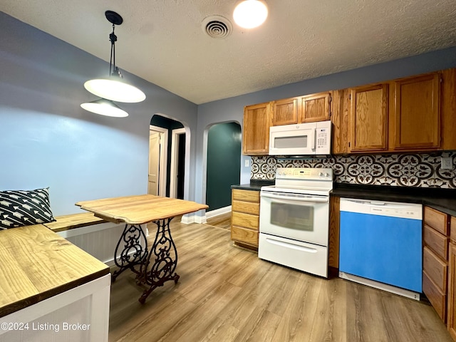 kitchen with decorative backsplash, light hardwood / wood-style flooring, pendant lighting, and white appliances