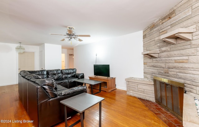 living room with a stone fireplace, ceiling fan, and hardwood / wood-style flooring