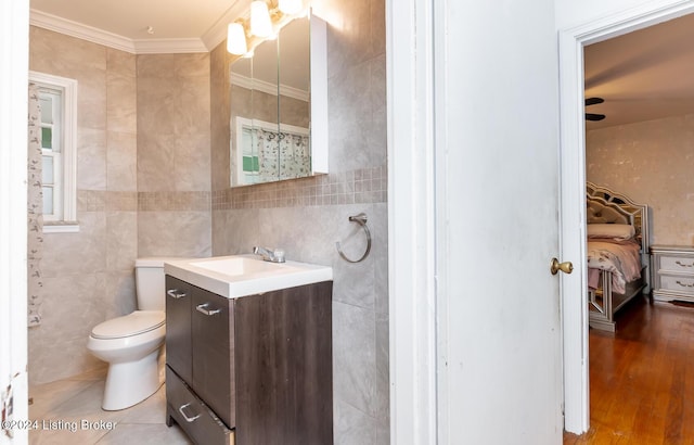 bathroom featuring hardwood / wood-style floors, vanity, ornamental molding, and tile walls