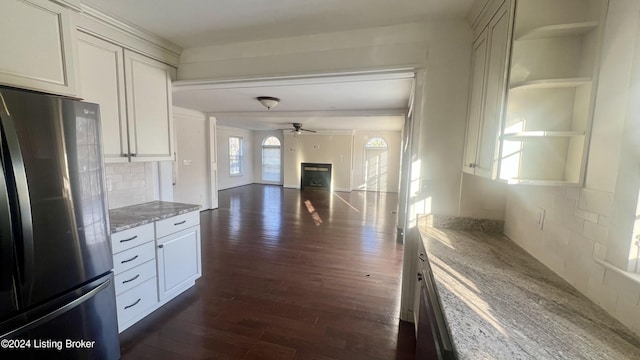 kitchen featuring stainless steel fridge, tasteful backsplash, light stone counters, ceiling fan, and dark hardwood / wood-style floors