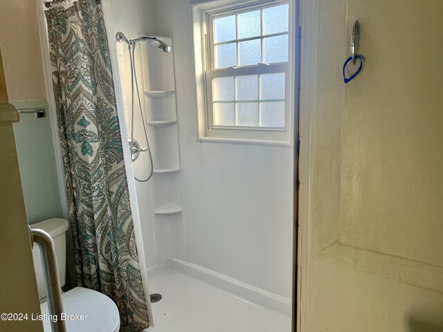 bathroom with a shower with curtain and toilet