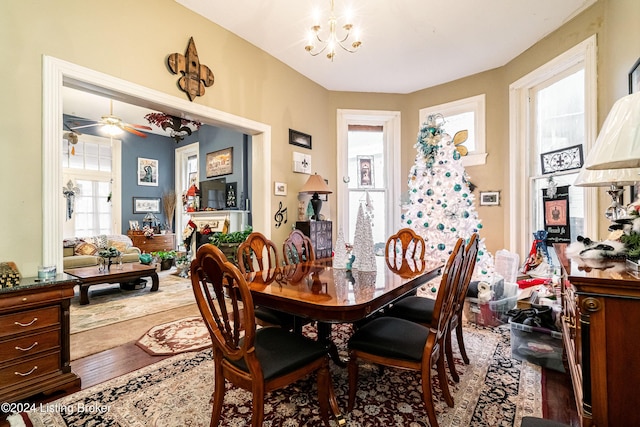 dining area with hardwood / wood-style floors and ceiling fan with notable chandelier