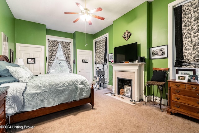 carpeted bedroom with ceiling fan and a brick fireplace