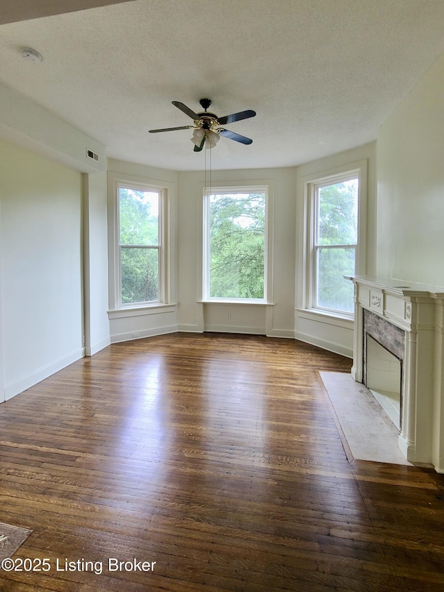 unfurnished living room with ceiling fan, dark hardwood / wood-style floors, and a textured ceiling