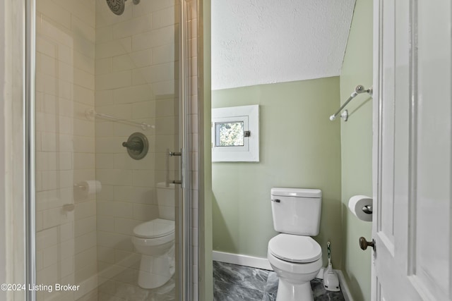 bathroom featuring toilet, a shower with shower door, and a textured ceiling