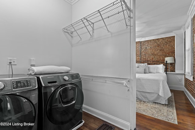 clothes washing area with washing machine and dryer, crown molding, brick wall, and dark hardwood / wood-style floors