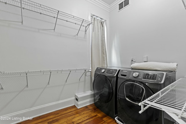 clothes washing area with separate washer and dryer, crown molding, and dark wood-type flooring