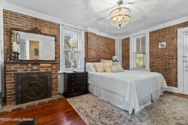 bedroom featuring dark hardwood / wood-style floors, ornamental molding, and brick wall