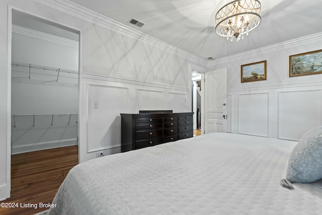 bedroom with dark hardwood / wood-style flooring, ornamental molding, and an inviting chandelier