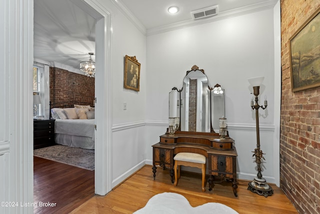 interior space with hardwood / wood-style flooring, ornamental molding, and brick wall