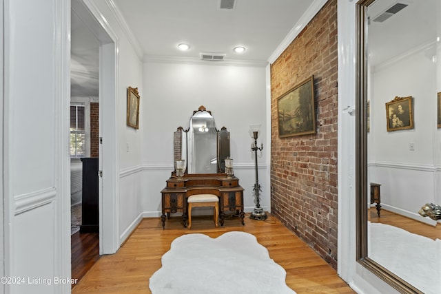 hallway featuring crown molding, light hardwood / wood-style floors, and brick wall