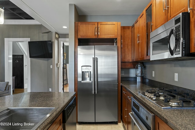 kitchen featuring light tile patterned flooring, stainless steel appliances, and dark stone countertops