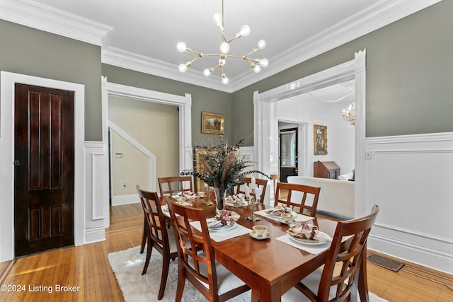 dining area featuring light hardwood / wood-style flooring, crown molding, and an inviting chandelier