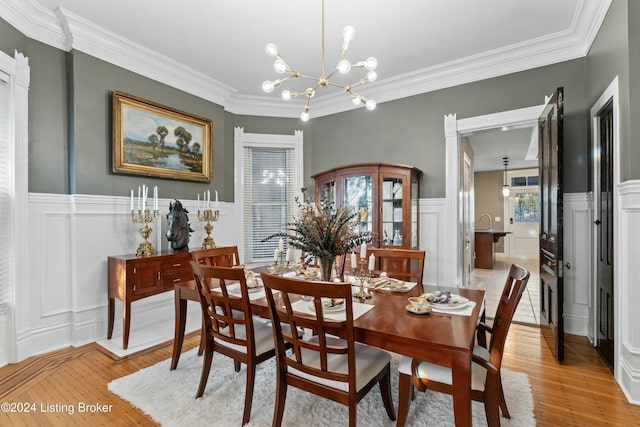 dining space with light hardwood / wood-style floors, crown molding, and an inviting chandelier