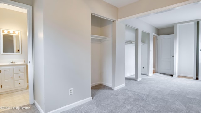 unfurnished bedroom featuring light colored carpet and ensuite bath