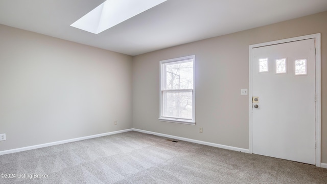 carpeted foyer entrance with a skylight