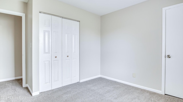 unfurnished bedroom featuring light carpet and a closet