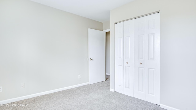 unfurnished bedroom with a closet and light colored carpet