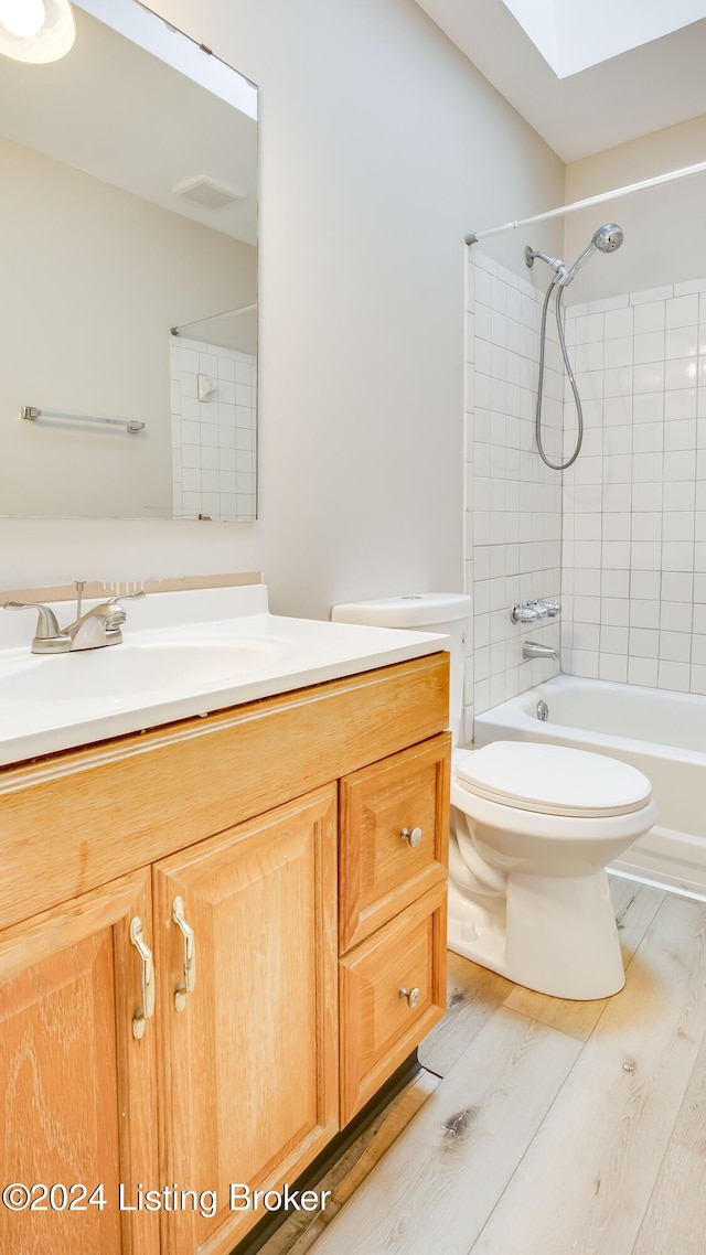 full bathroom with hardwood / wood-style flooring, tiled shower / bath combo, toilet, and vanity