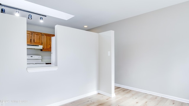 unfurnished room featuring a skylight and light hardwood / wood-style flooring