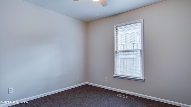 spare room featuring dark colored carpet and ceiling fan