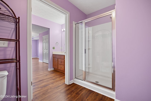 bathroom with vanity, a textured ceiling, hardwood / wood-style flooring, and a shower with door