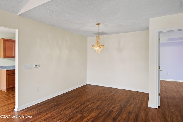 unfurnished room featuring a textured ceiling, dark hardwood / wood-style floors, and an inviting chandelier