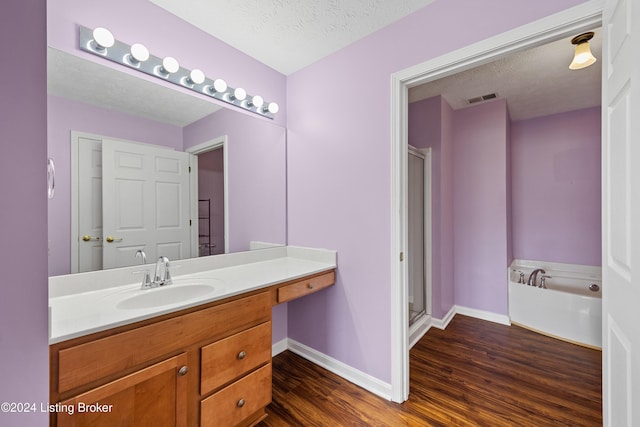 bathroom with plus walk in shower, vanity, a textured ceiling, and hardwood / wood-style flooring