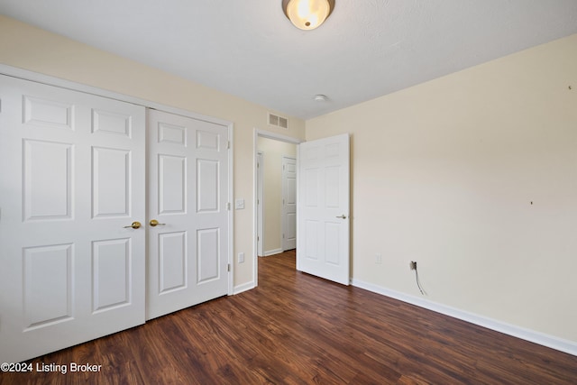 unfurnished bedroom featuring dark hardwood / wood-style flooring and a closet