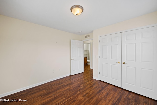 unfurnished bedroom featuring dark wood-type flooring and a closet