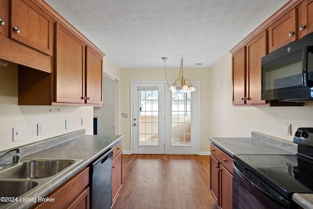 kitchen with a textured ceiling, dark wood-type flooring, sink, black appliances, and an inviting chandelier