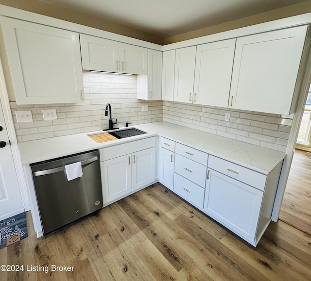 kitchen featuring light stone counters, stainless steel dishwasher, sink, light hardwood / wood-style flooring, and white cabinets