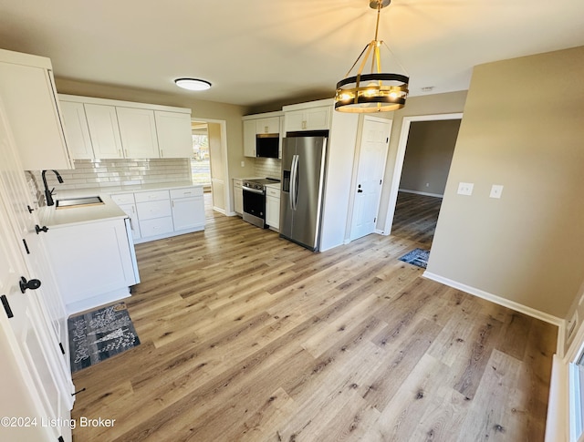 kitchen with white cabinetry, sink, stainless steel appliances, an inviting chandelier, and decorative light fixtures