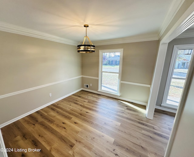 unfurnished dining area with hardwood / wood-style floors, ornamental molding, and a chandelier