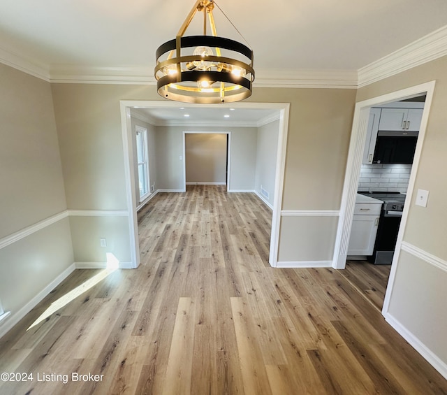 unfurnished dining area with light wood-type flooring, crown molding, and an inviting chandelier