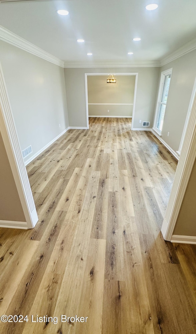 unfurnished living room with hardwood / wood-style floors and crown molding