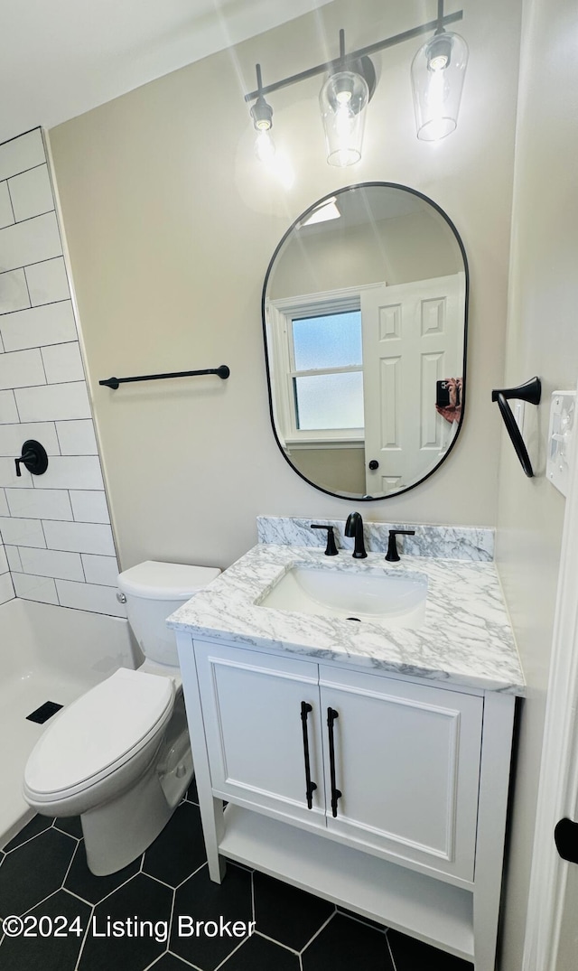 bathroom with tile patterned floors, vanity, toilet, and a tile shower