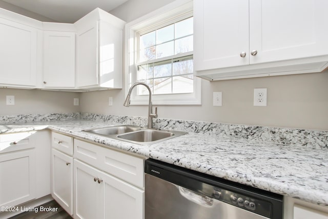 kitchen with light stone countertops, white cabinetry, sink, and stainless steel dishwasher